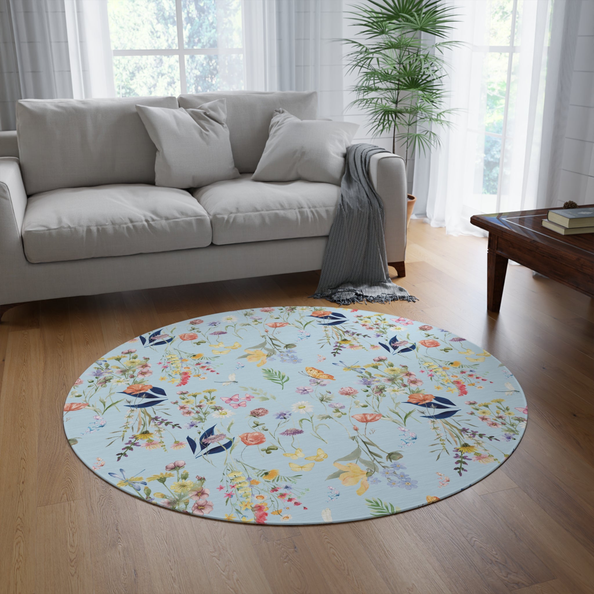 Round floral rug on a wooden floor in a living room with a sofa and coffee table.