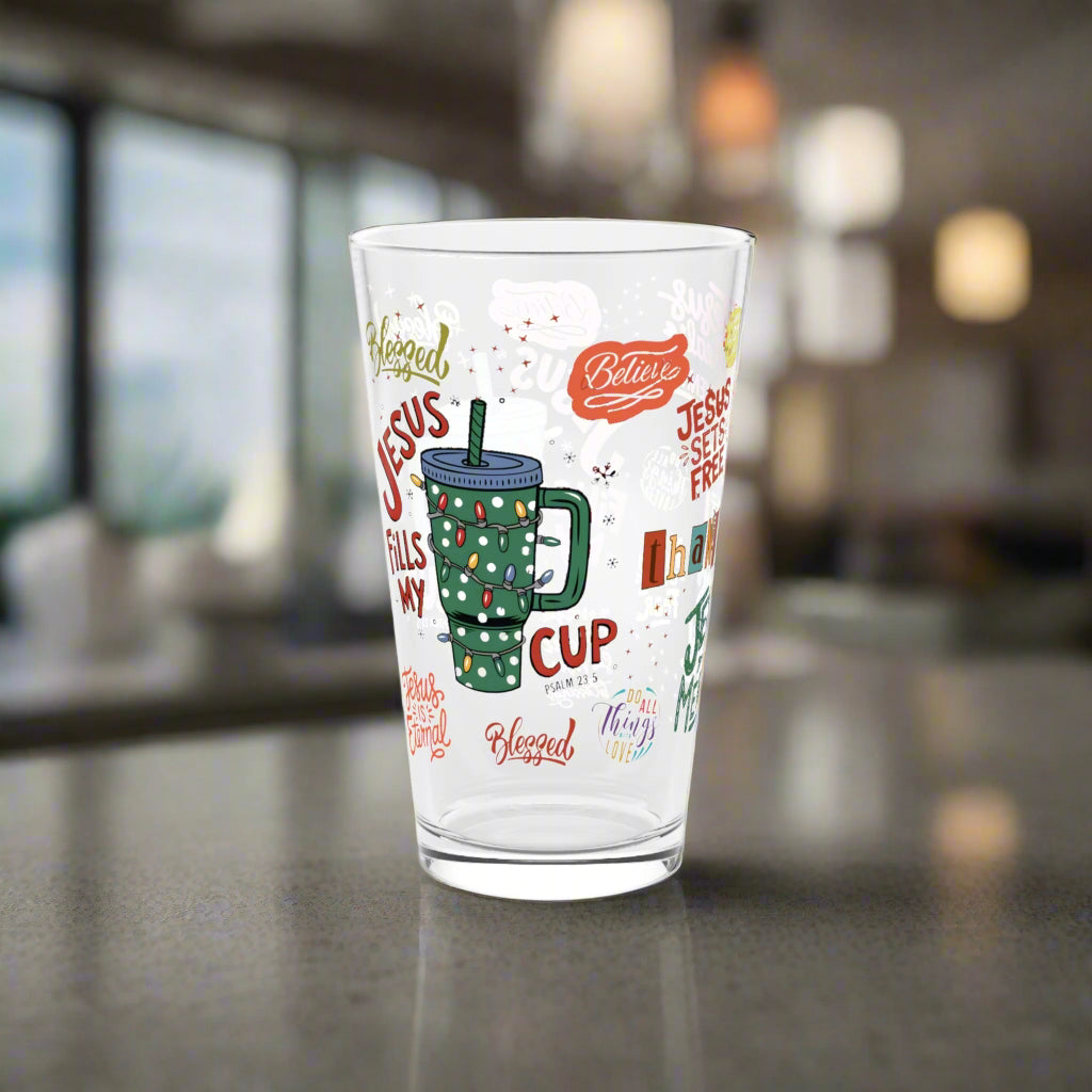 Clear glass mug with Christmas-themed text and graphics on a white background