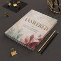 A hardcover journal titled 'ANSWERED. A PLACE TO REMEMBER WHAT GOD HAS DONE.