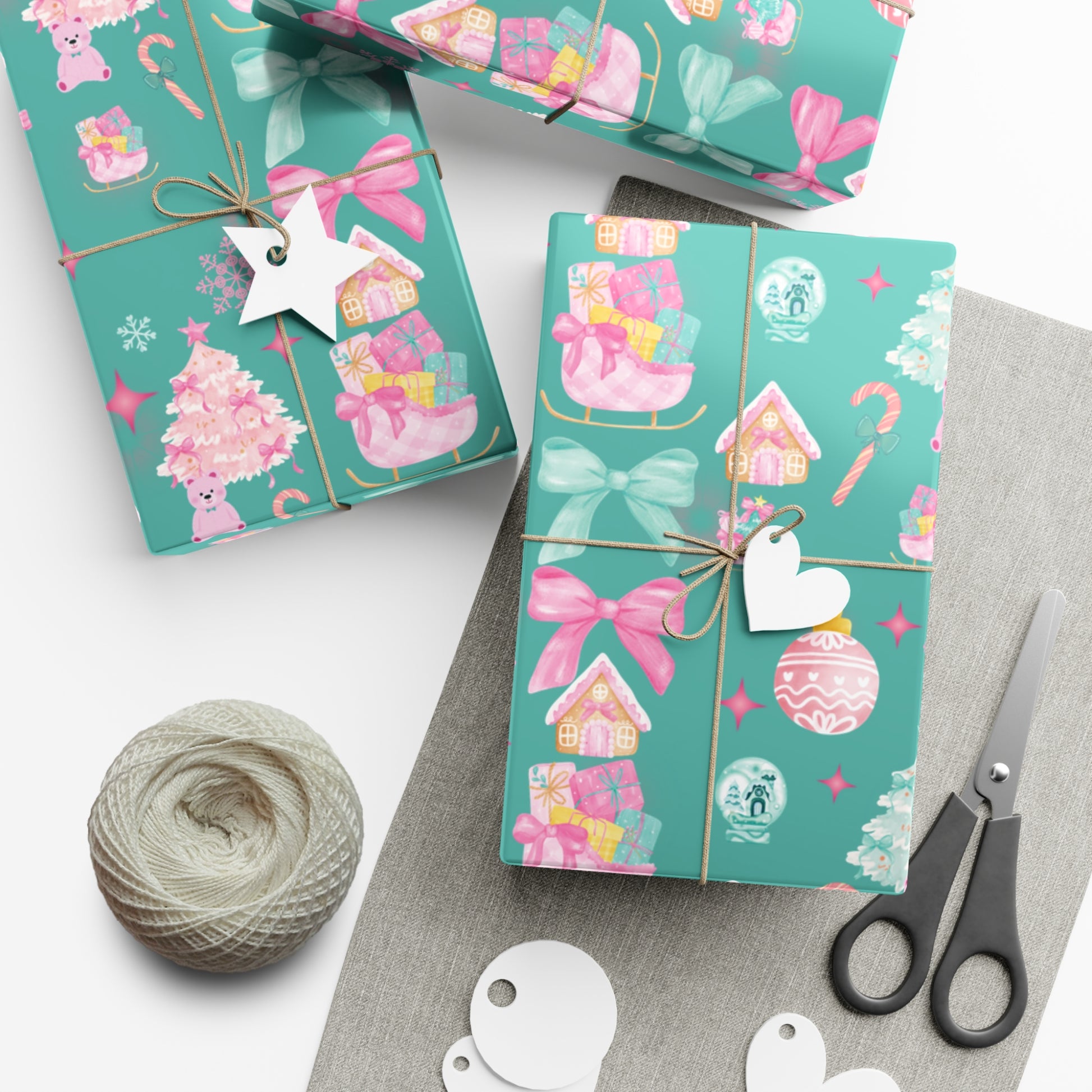 Turquoise gift boxes with pink decorative elements on a white surface with scissors and yarn.