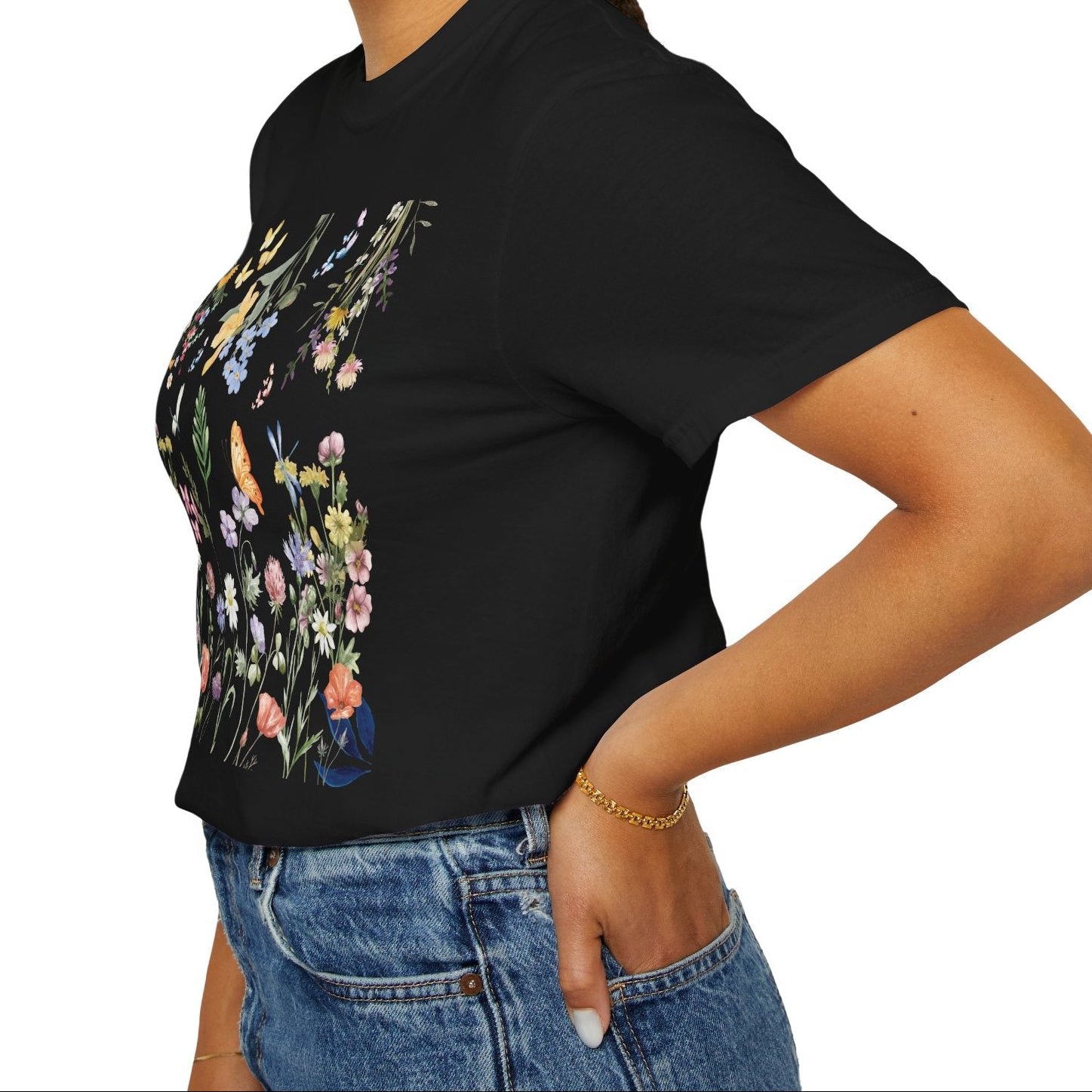 Woman wearing a black t-shirt with floral design and blue jeans on a white background