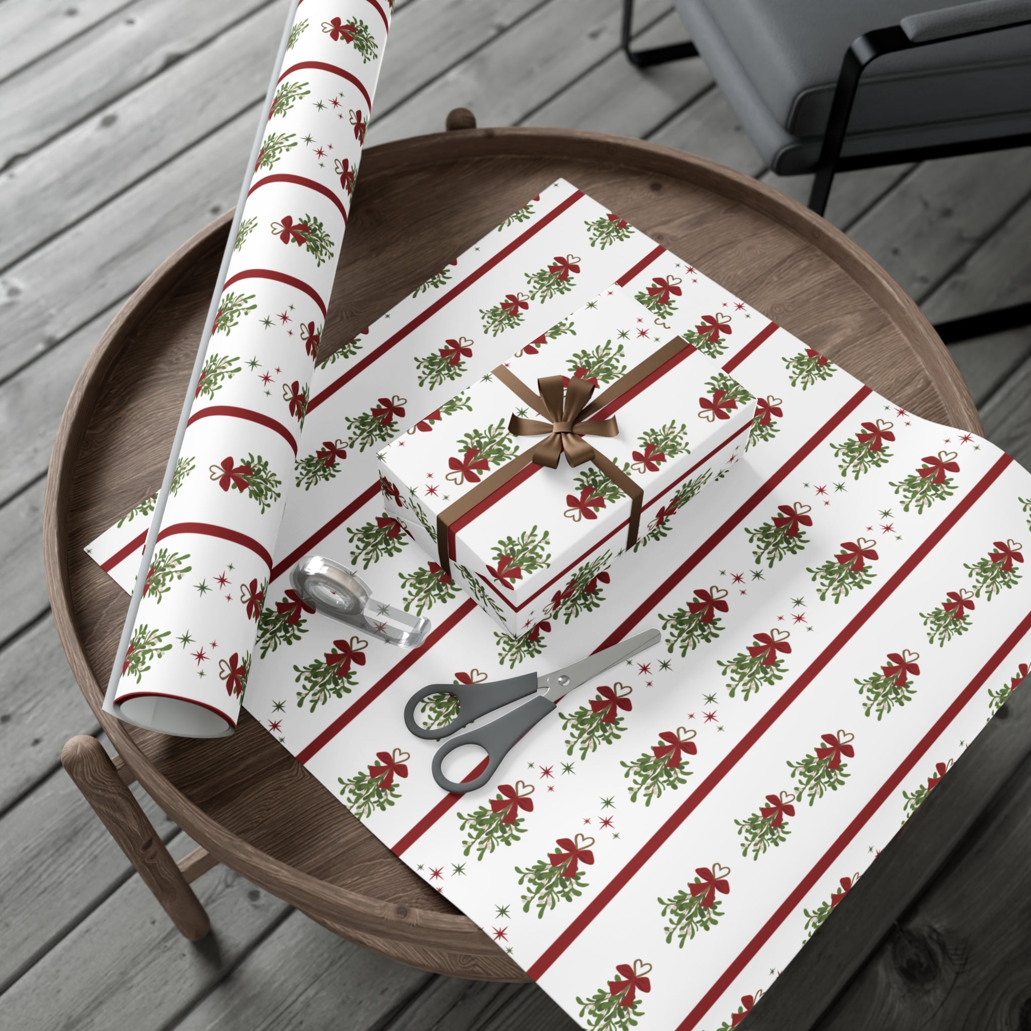 Christmas-themed wrapping paper with a box, scissors, and ribbon on a wooden tray.