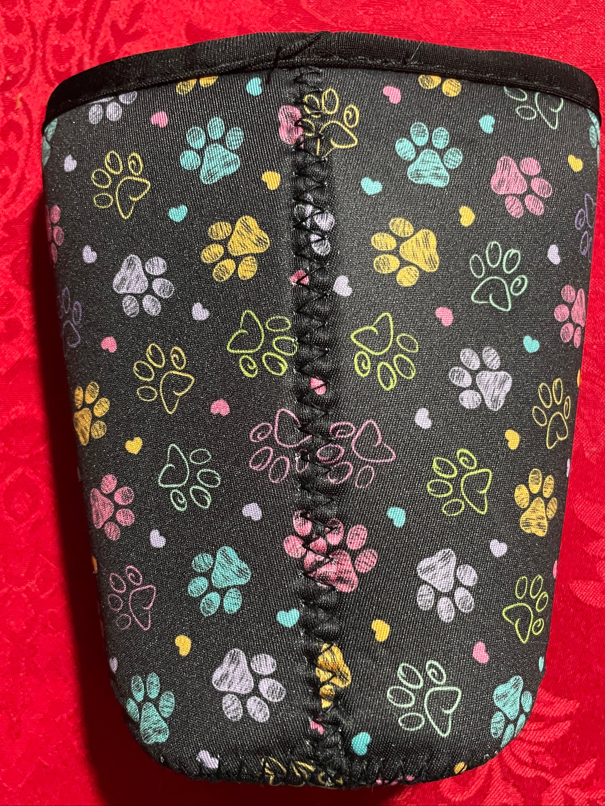 Black pouch with colorful paw prints on a red floral background
